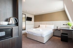 Chambre d’hôtel moderne et minimaliste avec lit confortable, mobilier design et grande fenêtre lumineuse dans un intérieur contemporain.