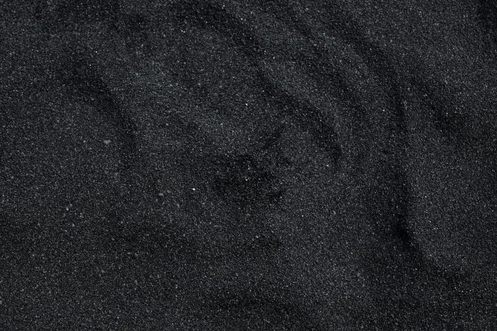 Gros plan sur la texture de sable noir de la plage de Waimea à Hawaï. Idéal en arrière-plan.